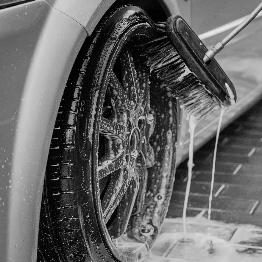 Close-up of car wheel being hand-cleaned with brush and foam at Tasman Autowash professional vehicle detailing service