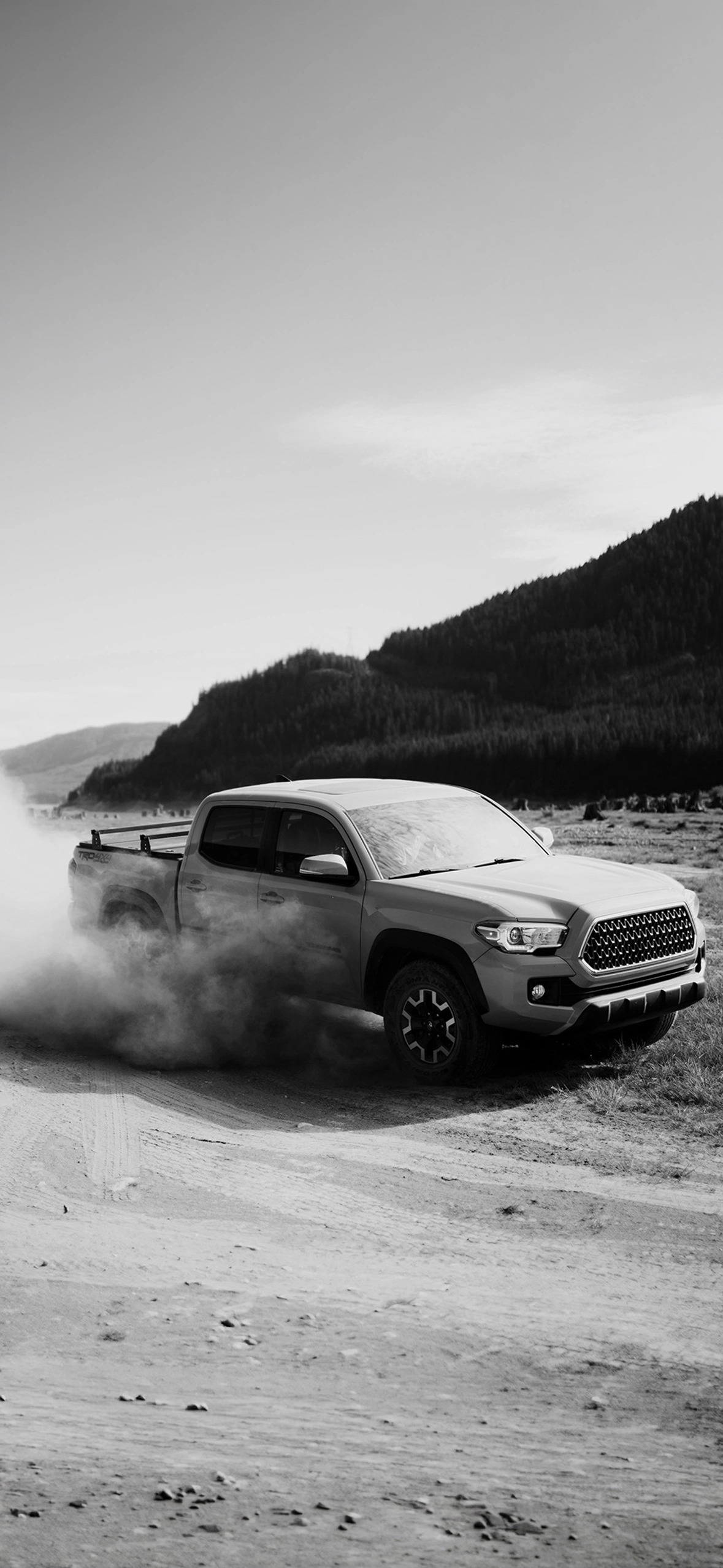 Dusty pickup truck driving on rural gravel road, highlighting off-road dirt removal and exterior cleaning by Tasman Autowash