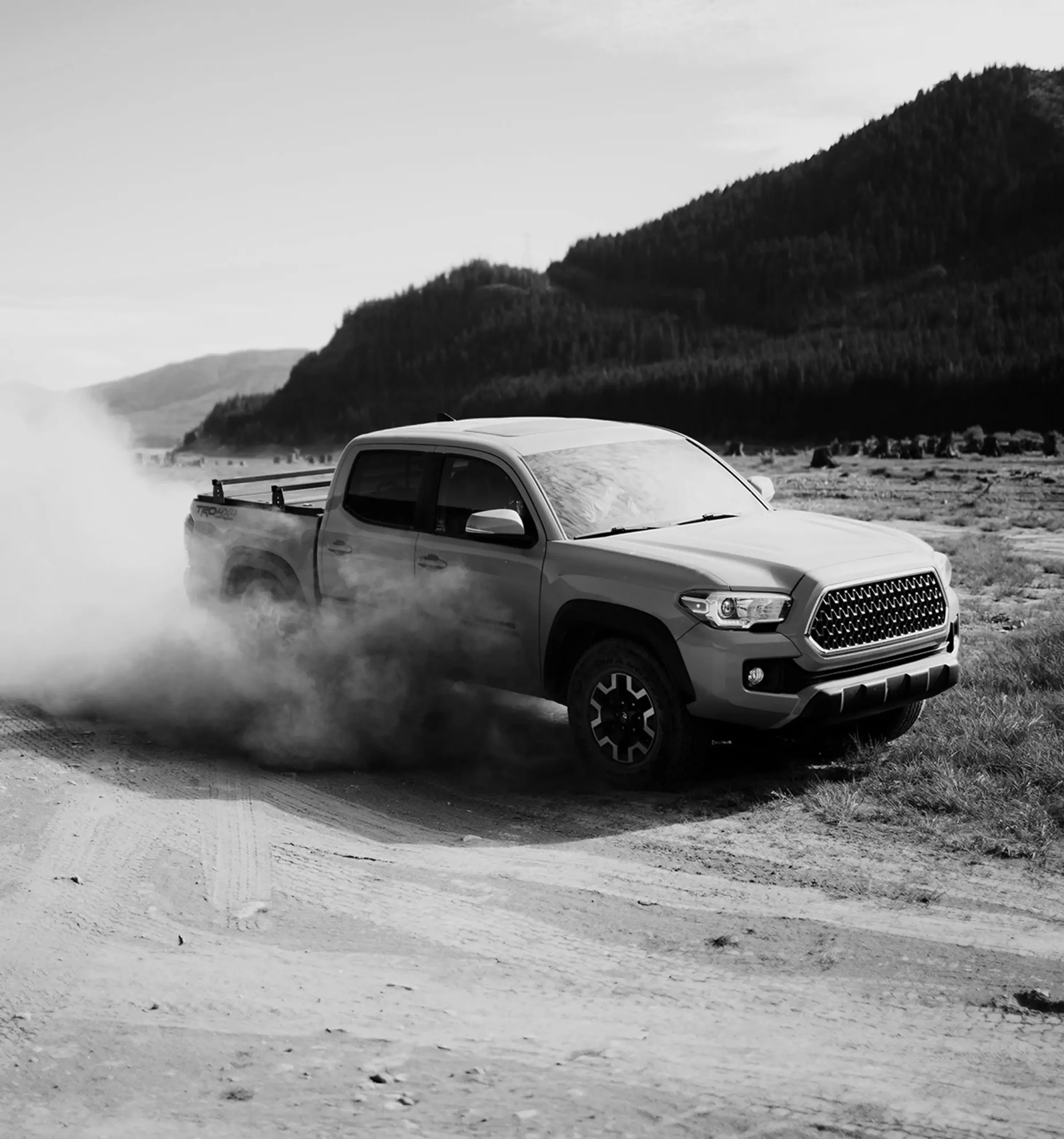 Dusty pickup truck driving on rural gravel road, highlighting off-road dirt removal and exterior cleaning by Tasman Autowash
